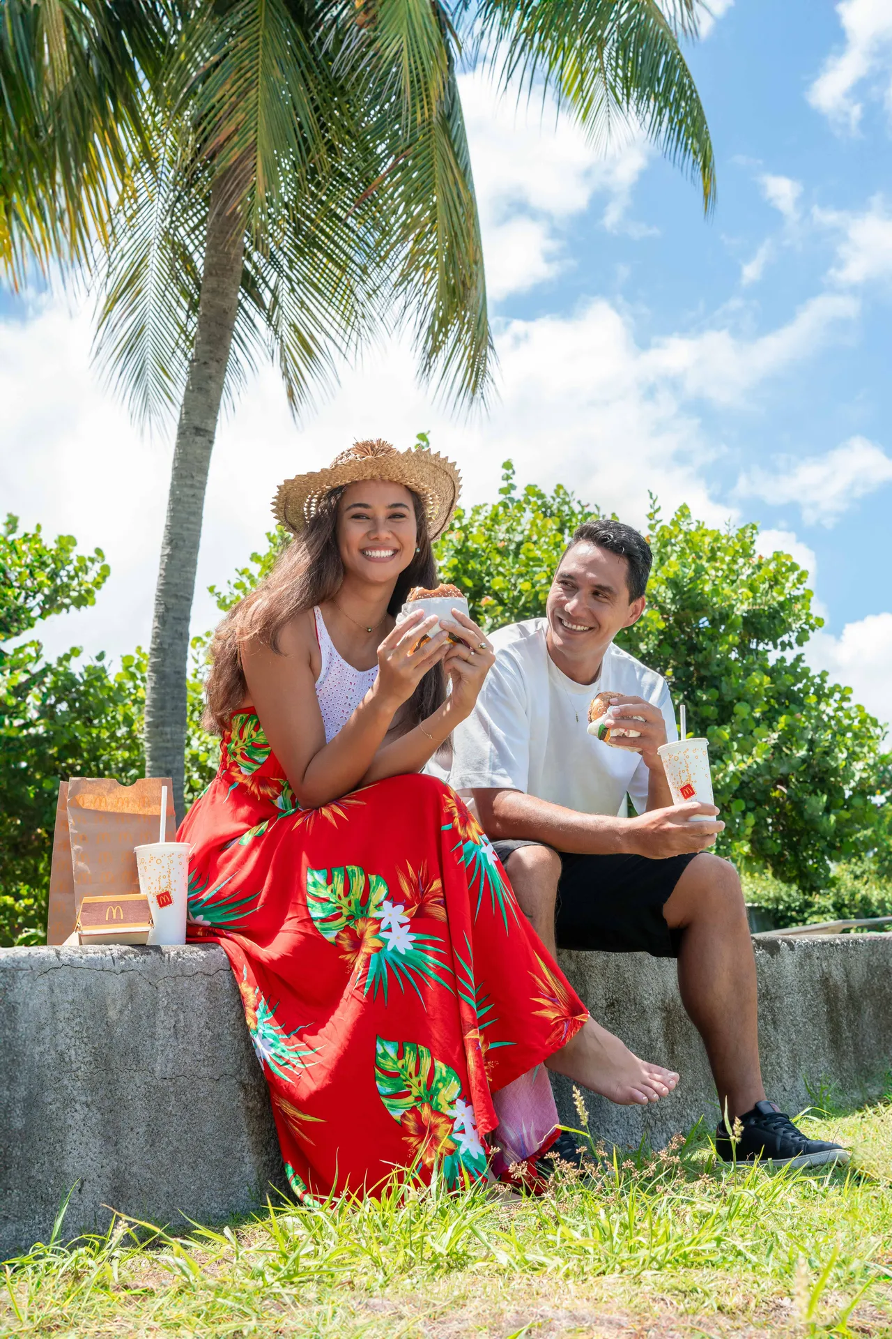 Two people with drinks beneath palm trees