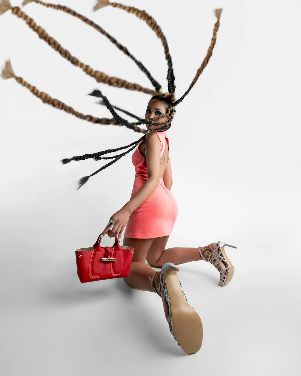 Fashion portrait in pink with a red bag and flowing braids