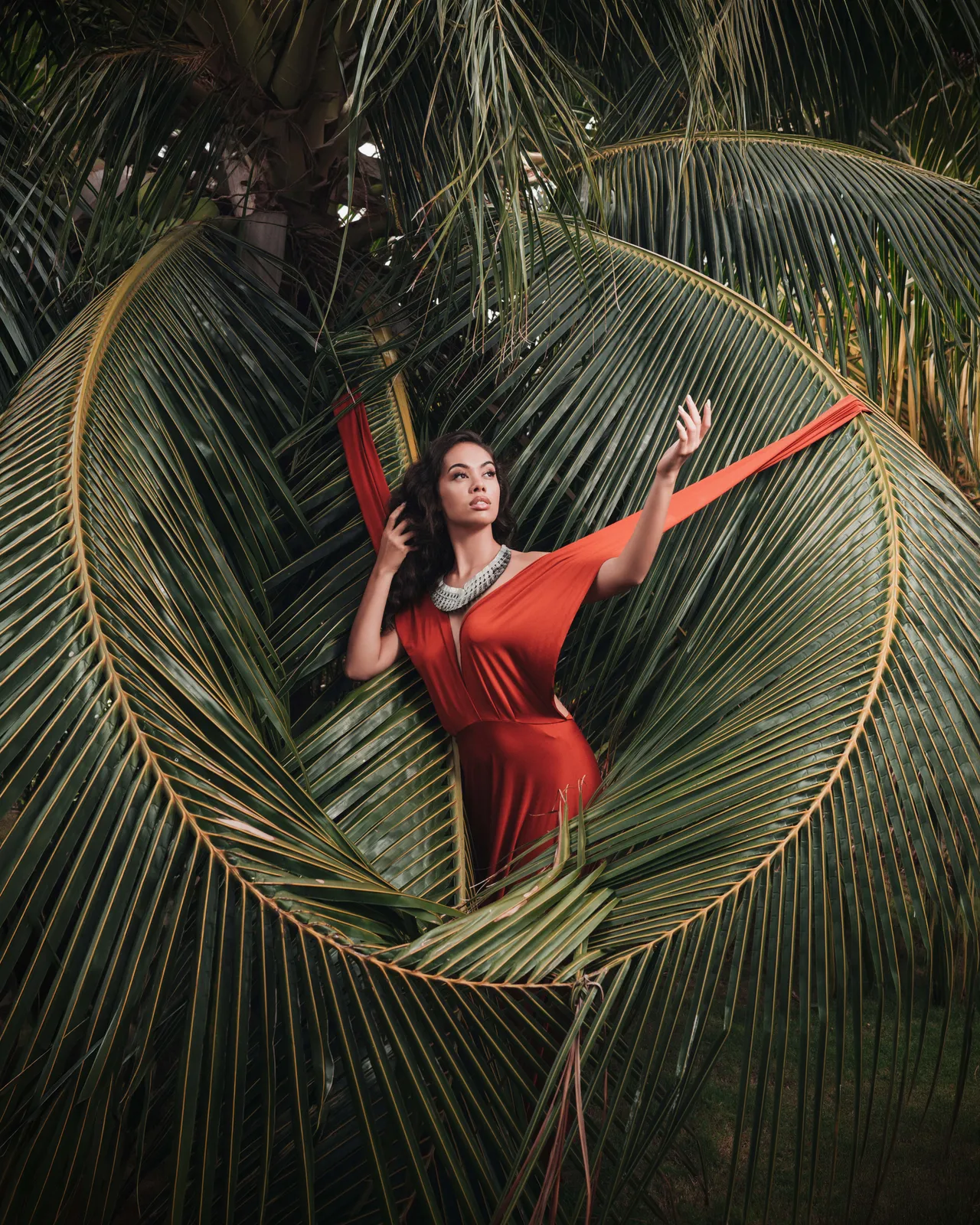 Red outfit framed by palm leaves