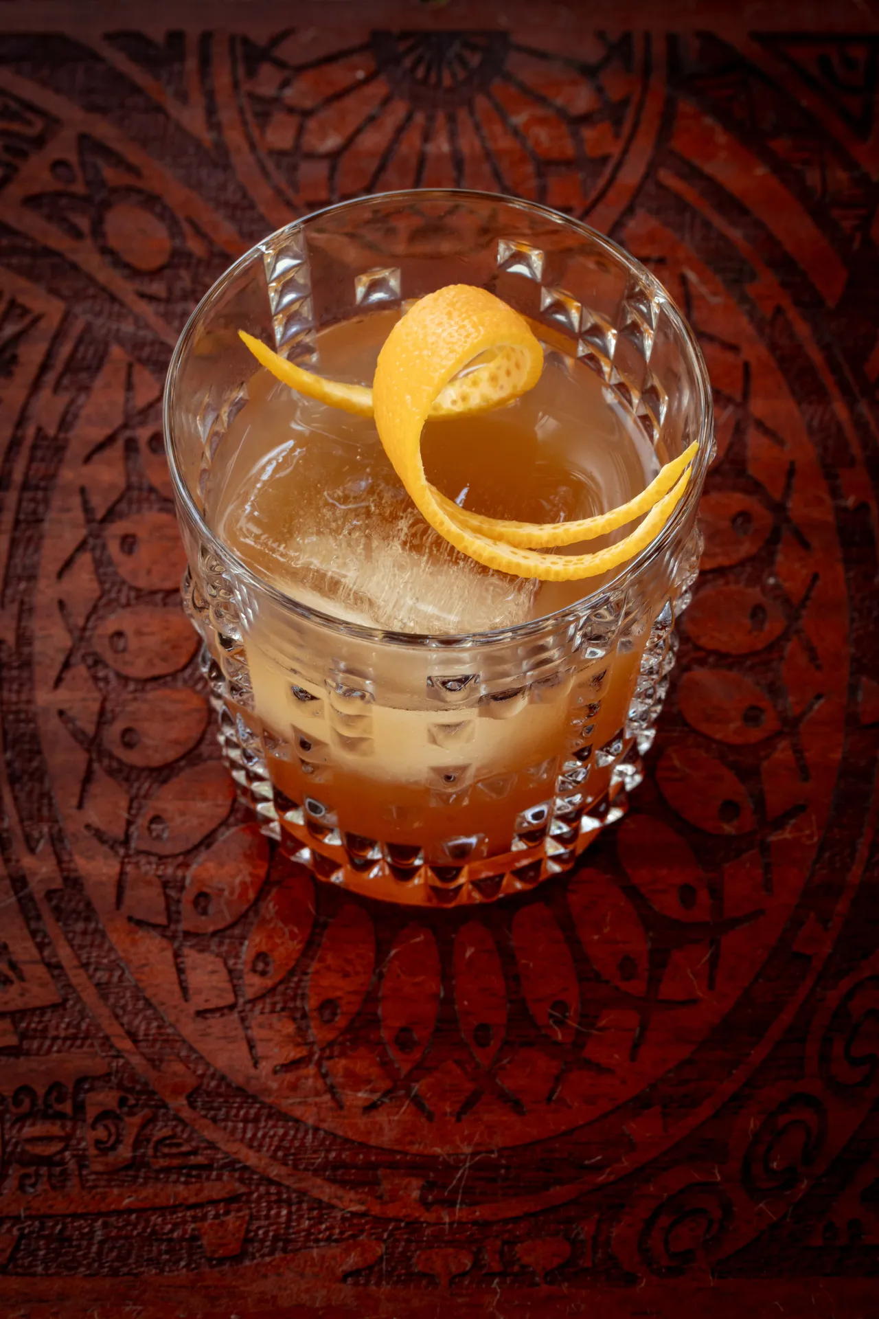 Cocktail and citrus peel on a carved table