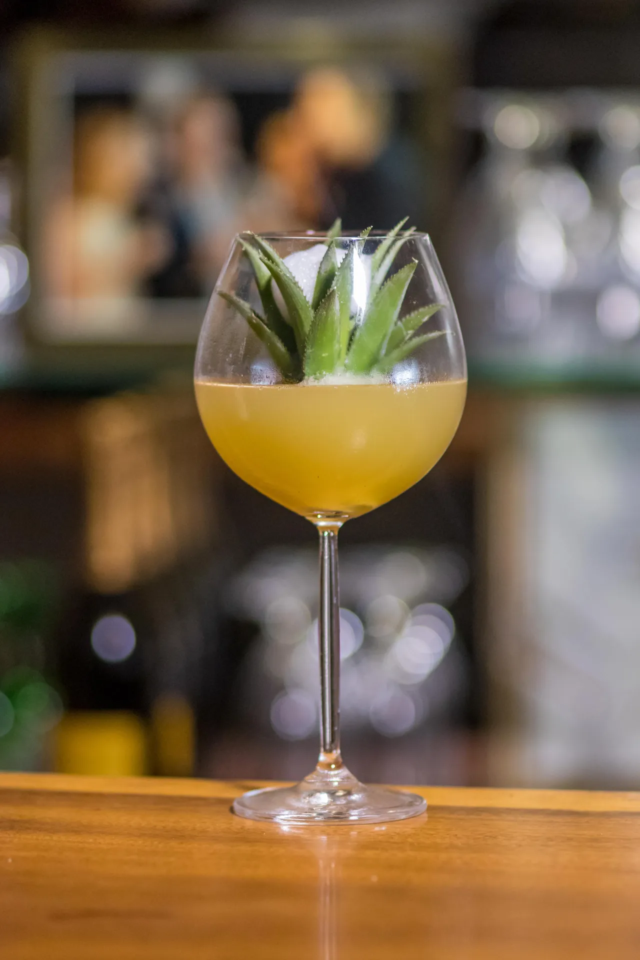 Yellow cocktail garnished with leaves